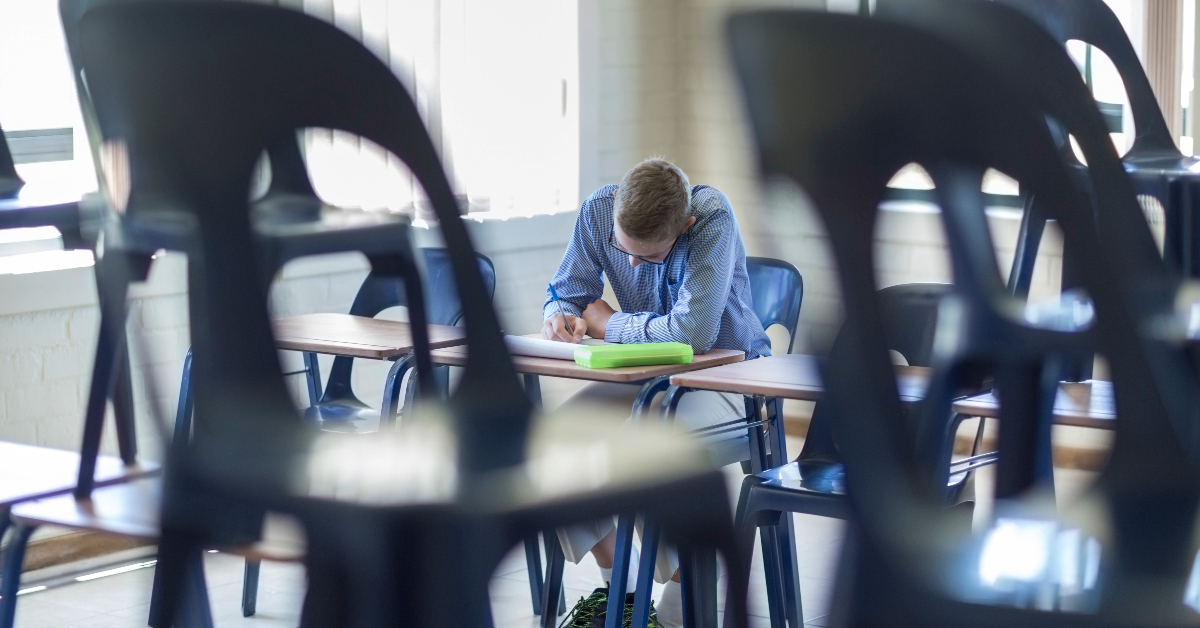 Schoolboy writing in classroom